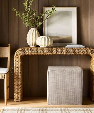 Gingham ottoman underneath rattan table and plaid rug