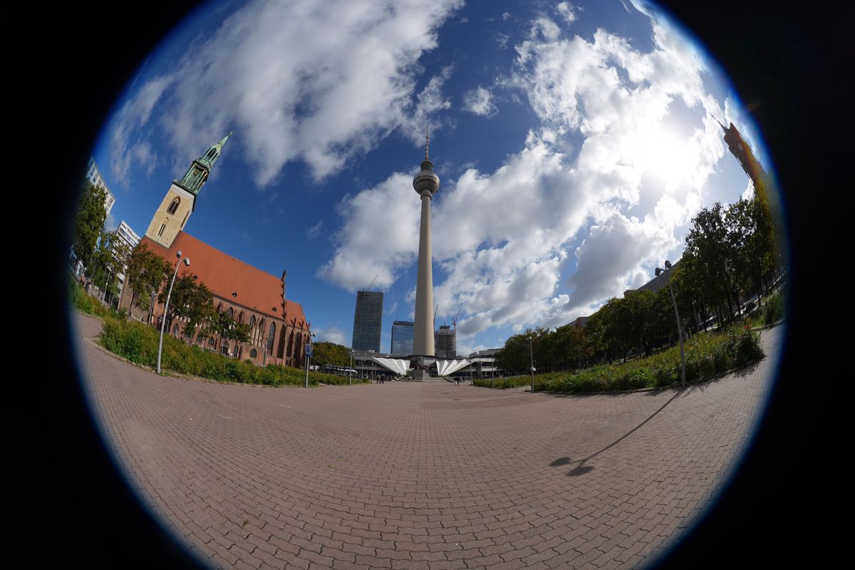 Circular fisheye view of Berlin&rsquo;s Fernsehturm TV tower and St. Mary&rsquo;s Church, surrounded by a black frame.