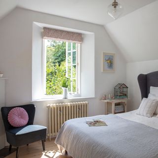 White bedroom in a country home in summer with window open and vintage furniture