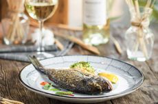 A dish of fish with a glass of wine