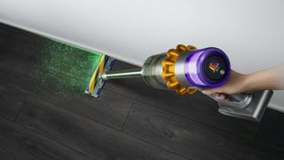 Dyson cordless stick vacuum cleaner used on a dark wood floor