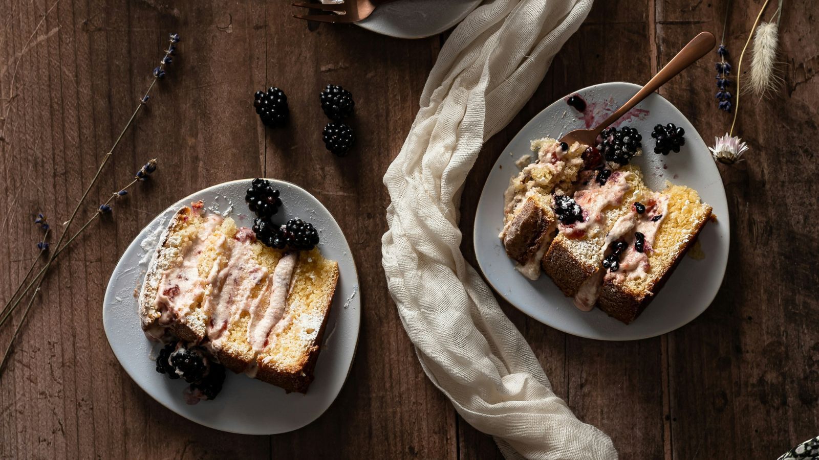 Aerial view of two slices of blackberry sponge cake with pale purple frosting