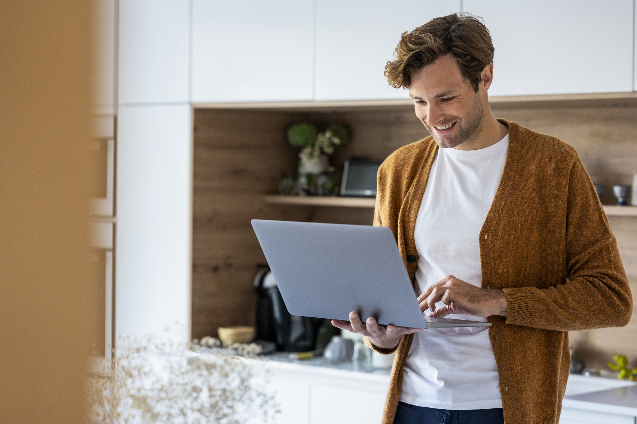 Adult man using laptop while standing in kitchen