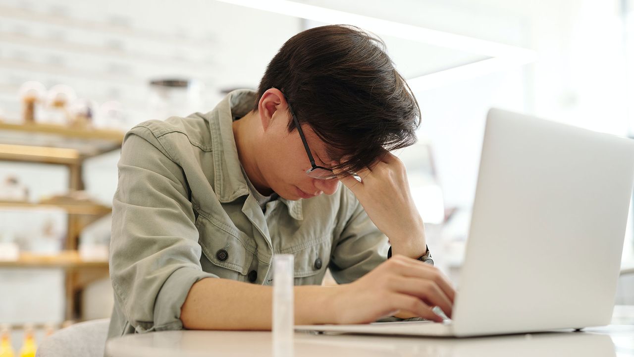 Man sitting by a laptop massaging his temples