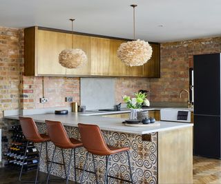 small kitchen diner with metallic fronted wall cabinets and patterned tiles to base of island unit with brown leather stools