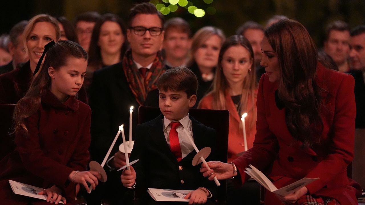 Princess Charlotte, Prince Louis and Kate Middleton holding lit candles and sitting at a carol service