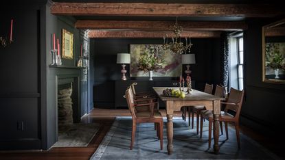 Small dining room with black painted walls and wood beams 