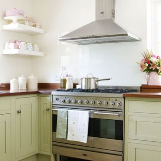 kitchen area with cooker with oven and extractor hood and white wall and shelves