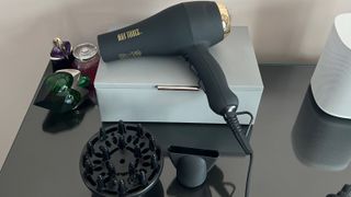 The Hot Tools Pro Signature Salon Ionic AC motor hair dryer on top of a leather box on a glass-topped surface