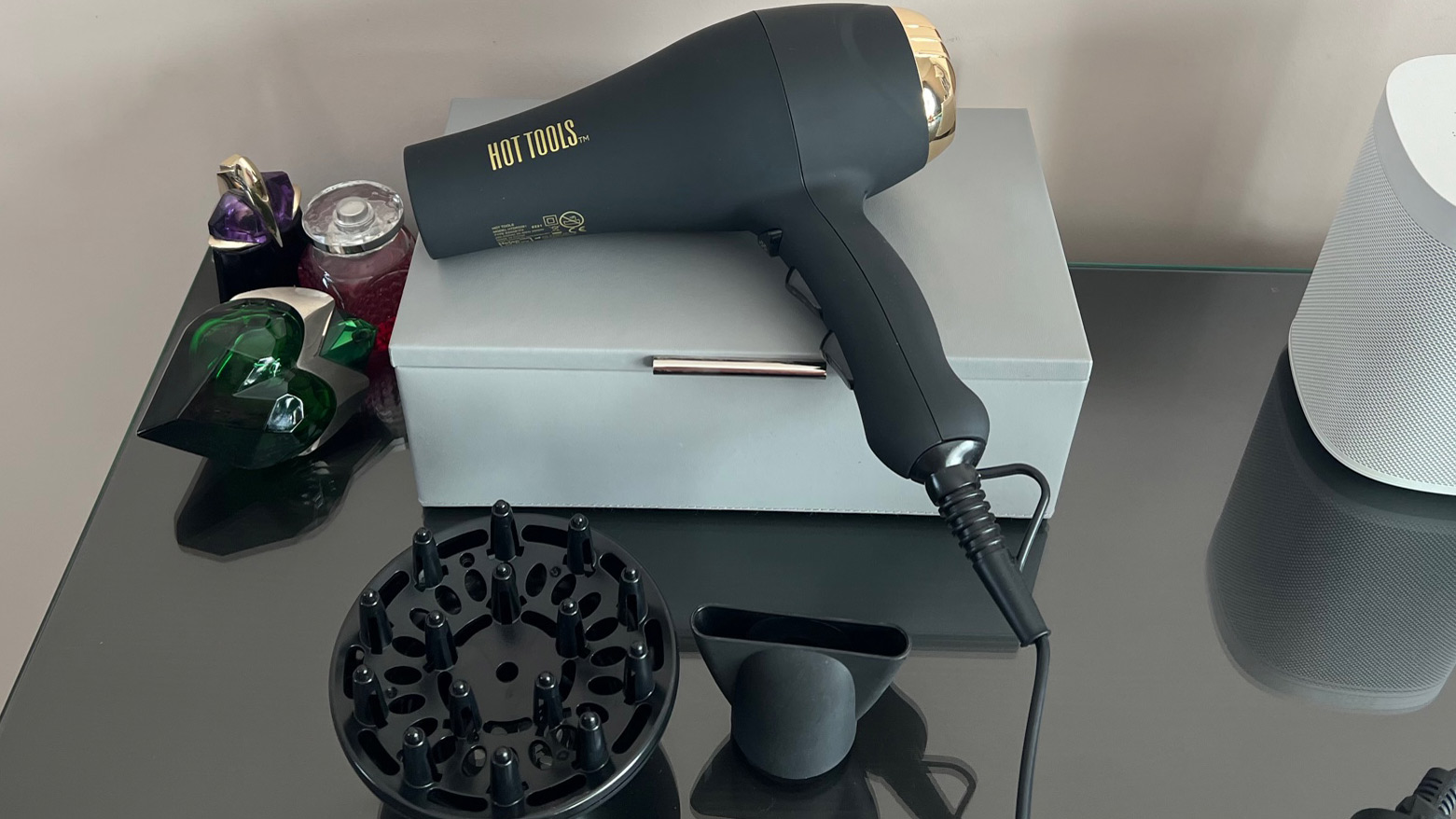 The Hot Tools Pro Signature Salon Ionic AC Motor Hair Dryer pada wadah kulit di permukaan kaca