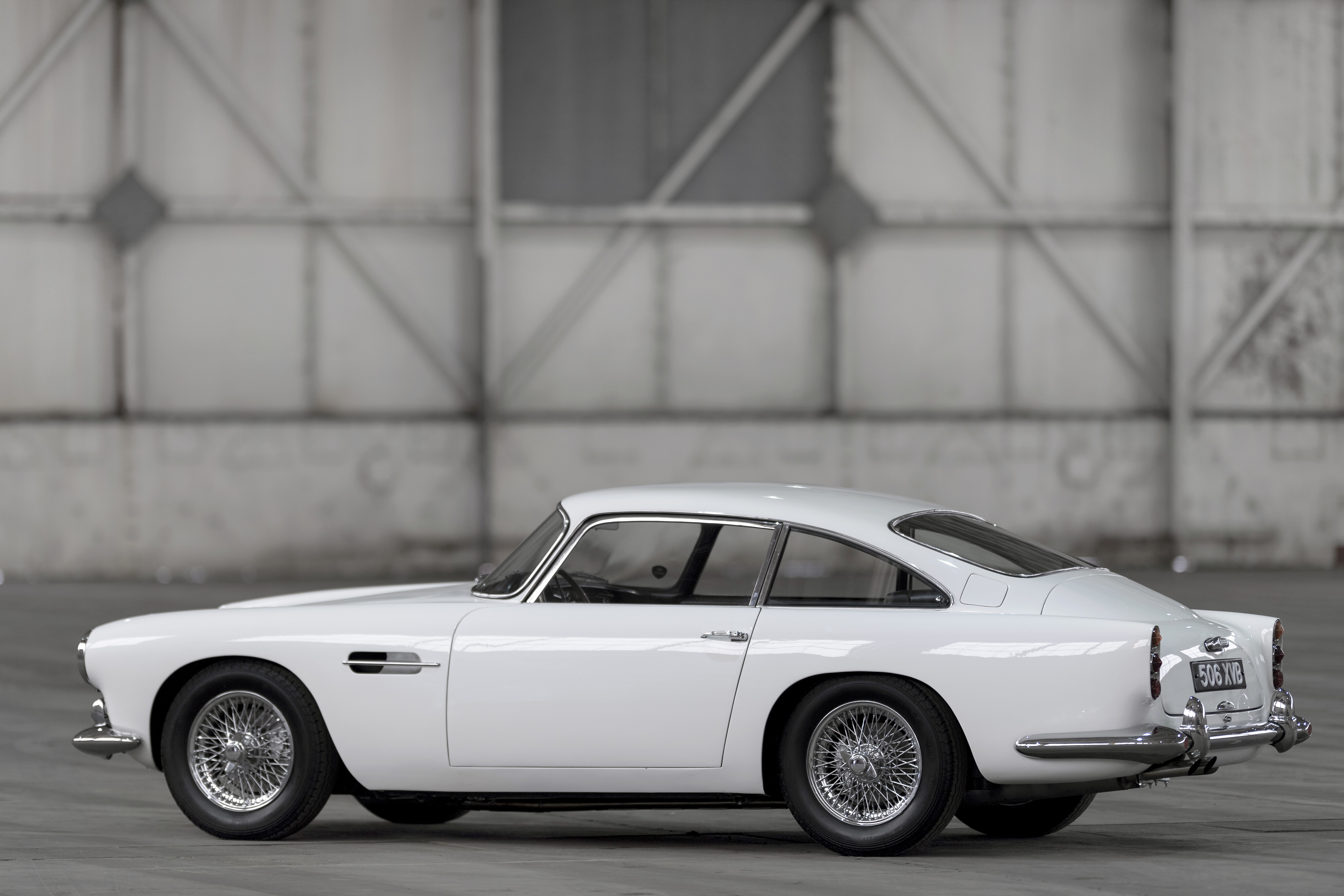 Details of the Aston Martin DB4, painted white, in a grey airplane hangar