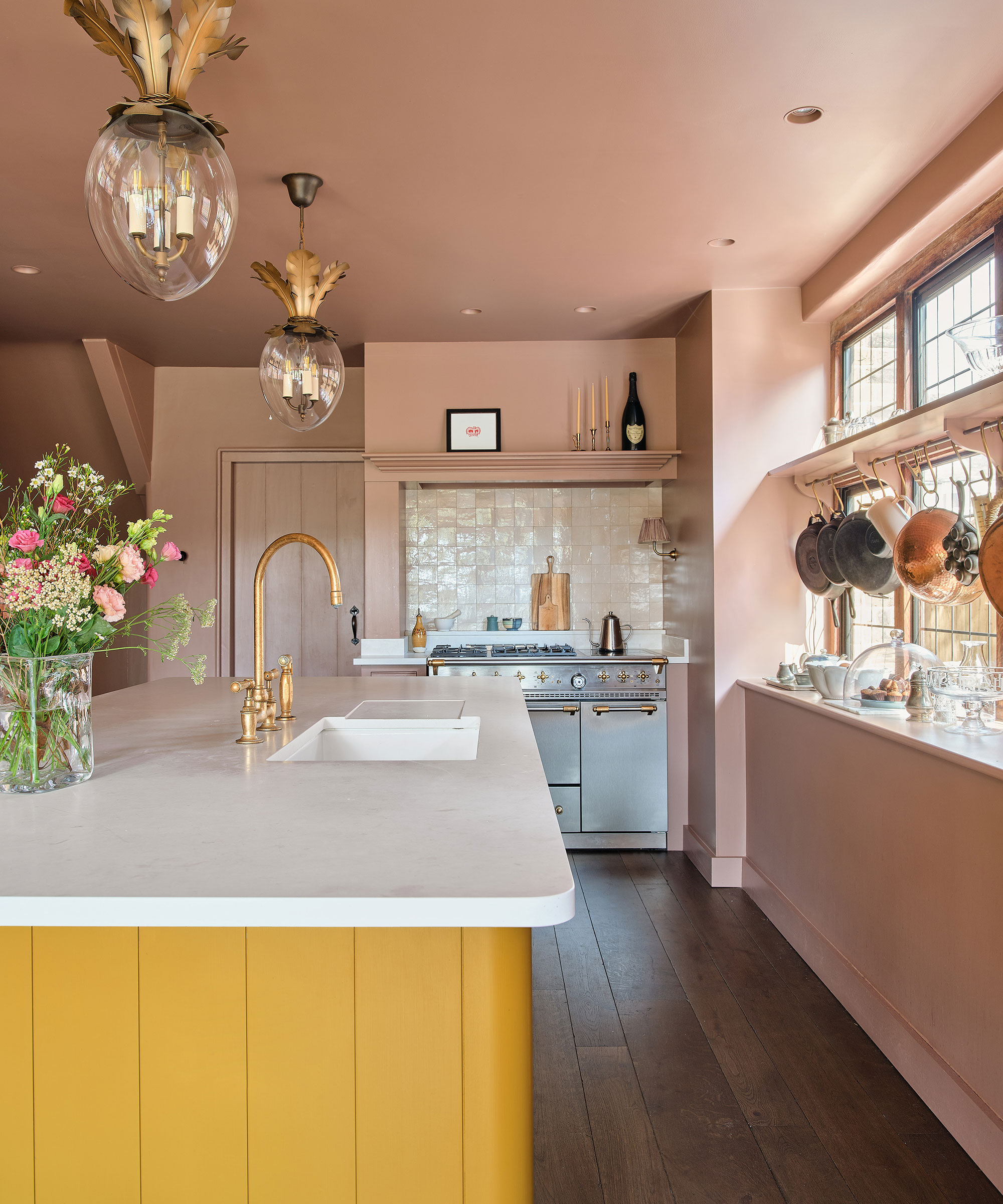 pink kitchen with yellow kitchen island and wide plank wooden flooring