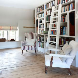 white walls with bookcase wooden flooring white wooden lader and chairs