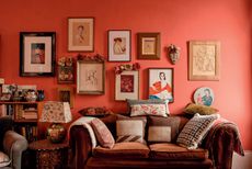 red living room with lots of art above a sofa