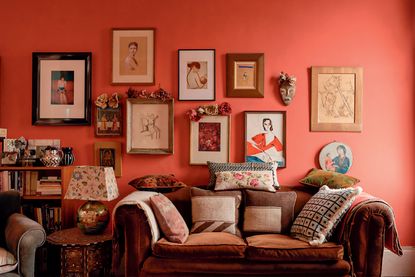 red living room with lots of art above a sofa