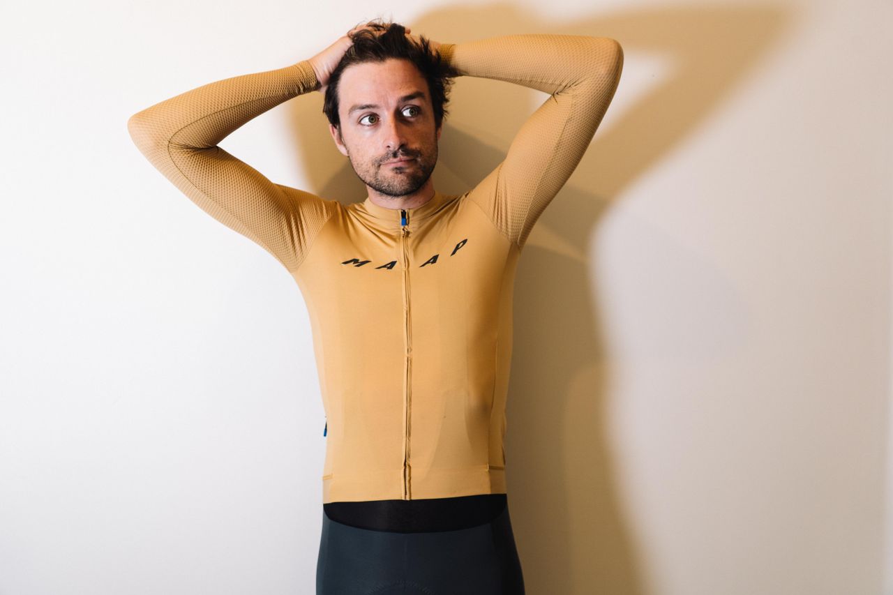 A white man in a tan jersey against a white wall