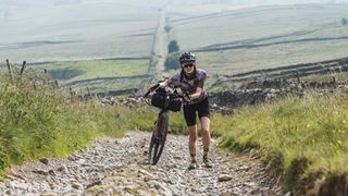 A rider pushing her bike on the Pennine Rally