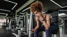 Woman in gym looks at phone