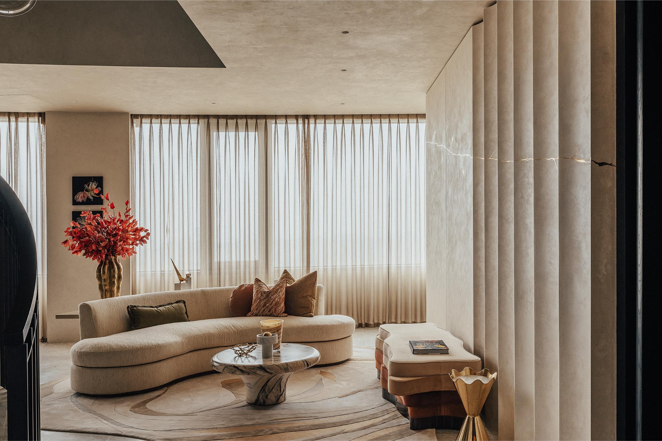 A curved sofa in a warm oatmeal hue in a contemporary living room