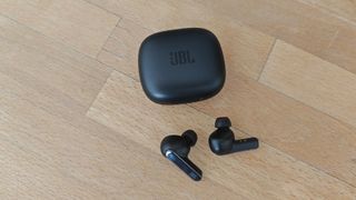 JBL Live Pro 2 review: earbuds outside of their case on a wooden table