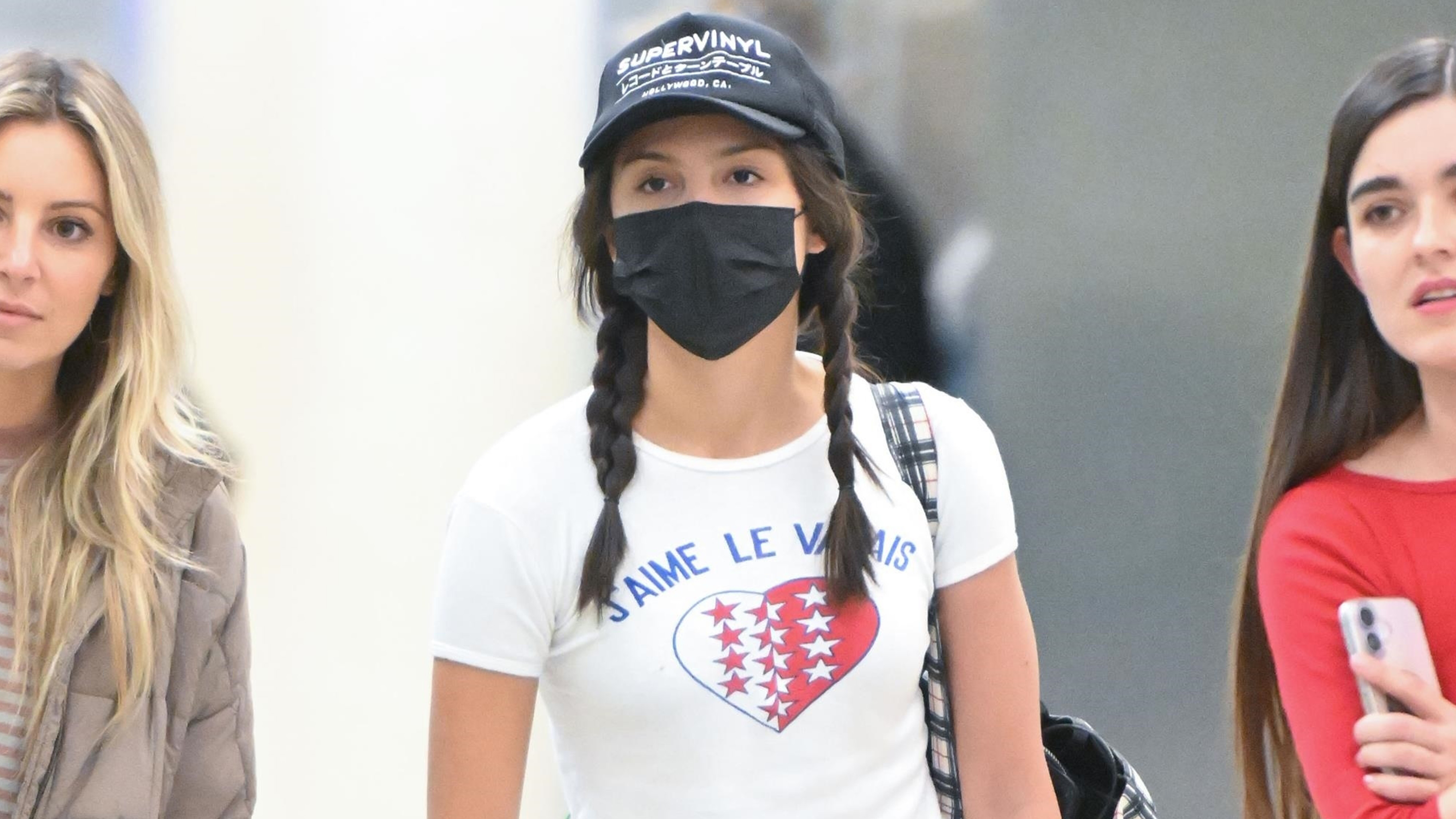 Olivia Rodrigo was spotted arriving back in the United States at JFK in New York after a trip in Iceland.. She wore a white graphic T-shirt, Leset Nando white pants, and Ugg Tazzlita mules.