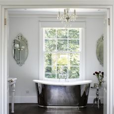 bathroom with white wall chandelier and bathtub