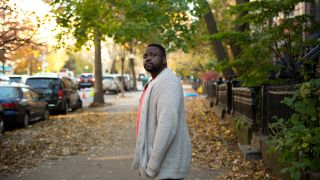 Brian Tree Henry stands on a street with fallen leaves in New York City in 'The Outside Story'