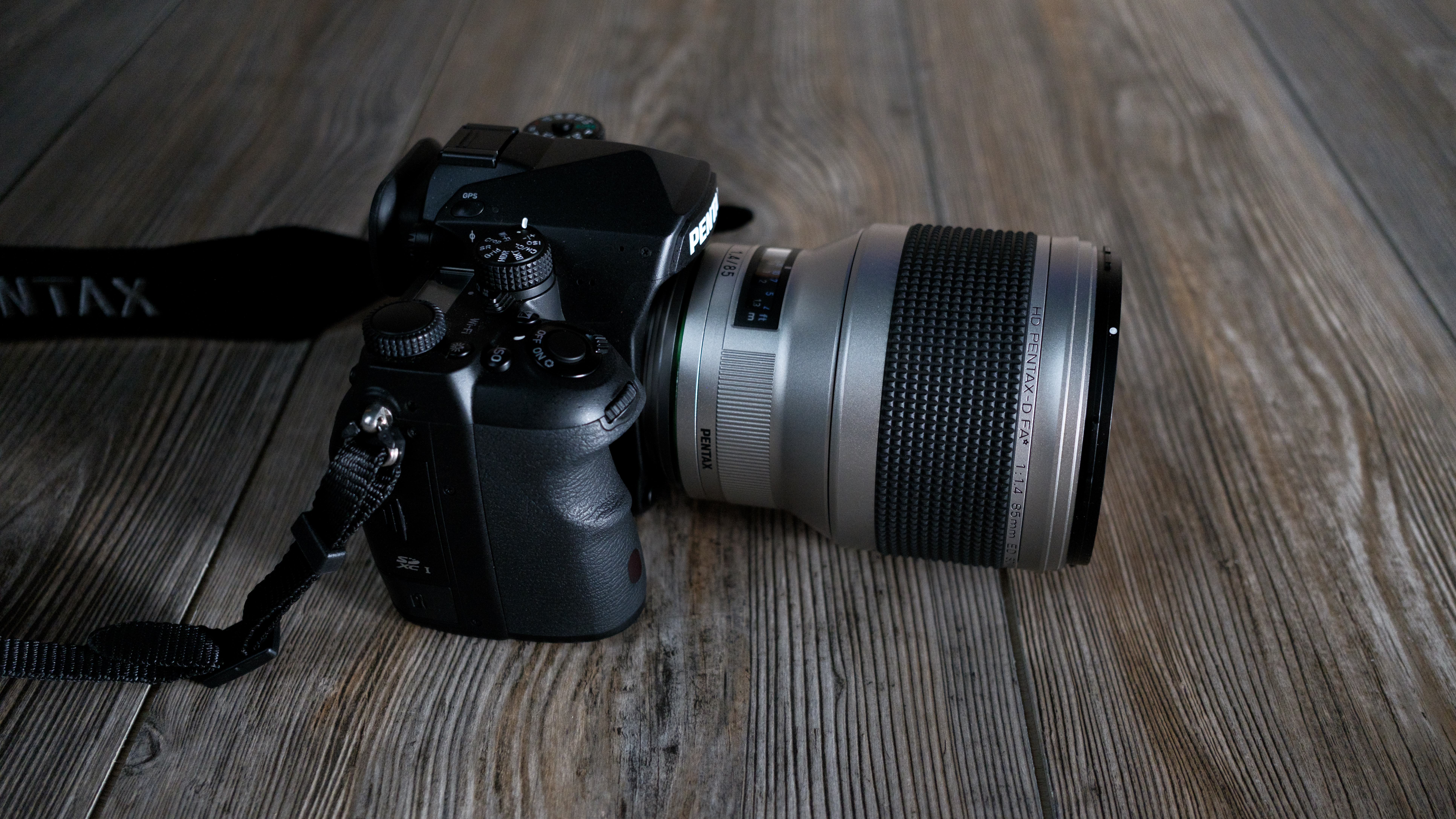 The Pentax 85mm f/1.4 SDM AW on a wood background