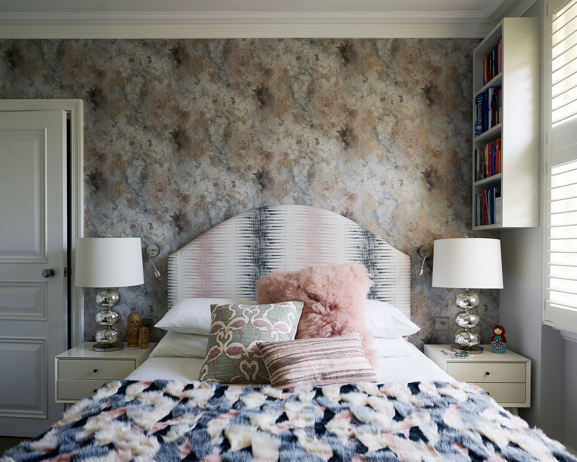 Impressionist-inspired wallpaper behind a bed with an upholstered blue, pink and white headboard