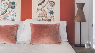 A white comforter on a bed against a red wall.