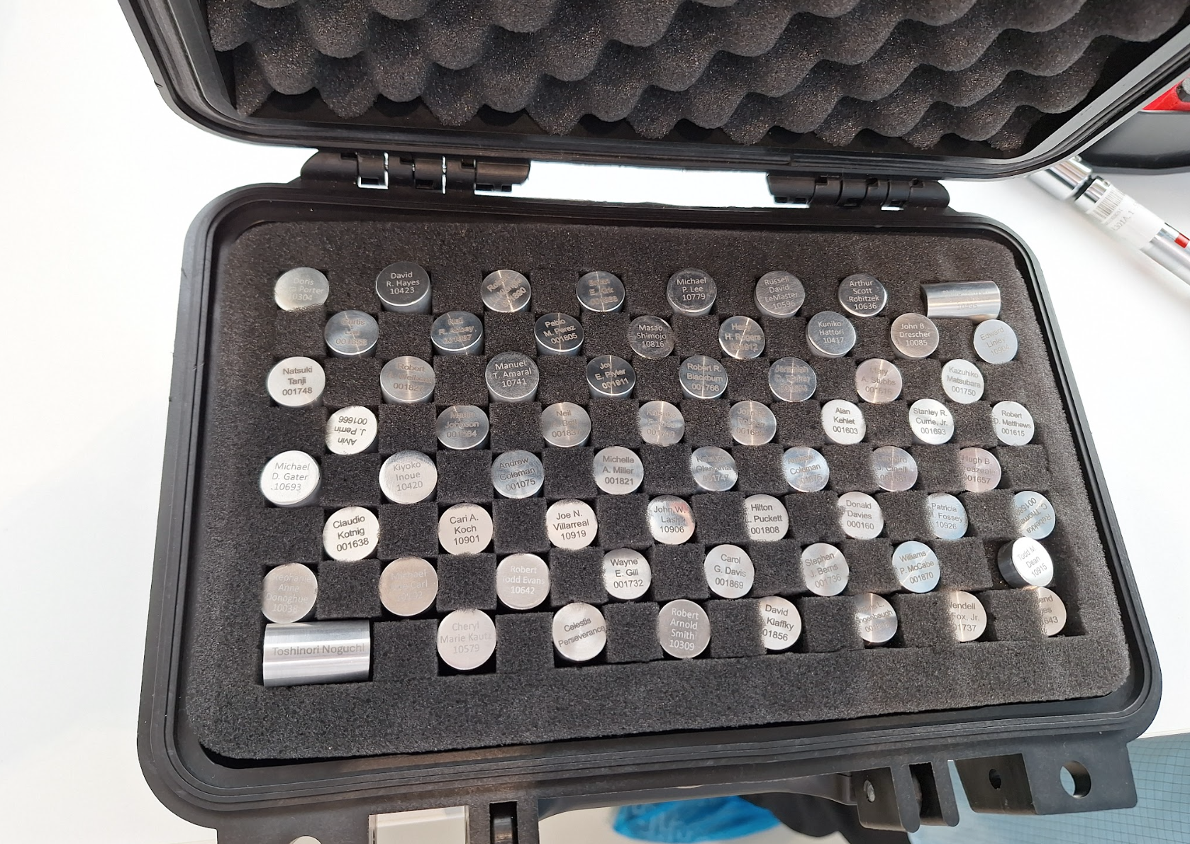 A black carrying case with dozens of silver capsules