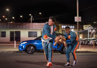 (L-R) Mark Wahlberg as Huck, Kevin Hart as Sonny, cross a street carrying a giant turtle, in Me Time