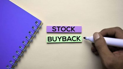 stock buyback written on purple and green paper next to a blue notebook