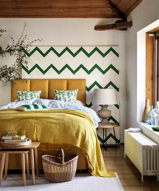 bedroom with yellow bed, green zig zag wall art and yellow throw on bed