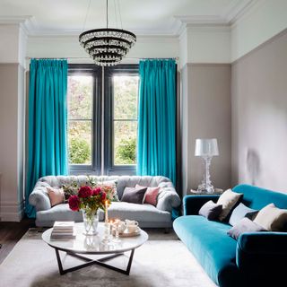 Grey living room with chandelier, turquoise sofa and curtains