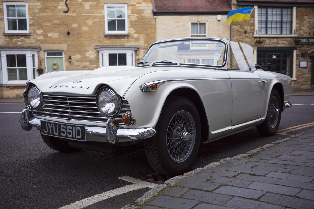 A classic white car parked next to a curb