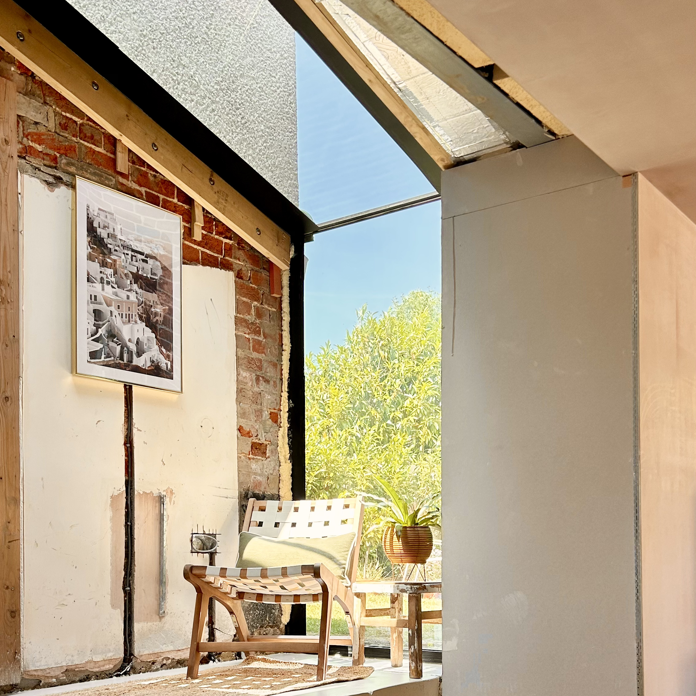 Chair under a glass roof next to a bare brick wall
