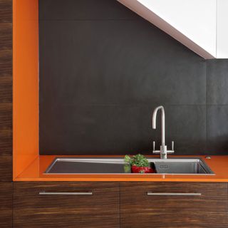 kitchen room with orange and black wall and kitchen sink