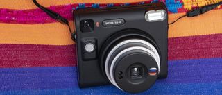 Fujifilm Instax SQ40 camera with a vibrant multi-color cloth backdrop
