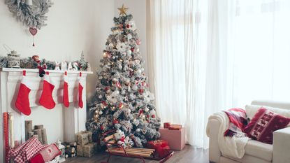 An image of a Christmas tree next to a fireplace with red stockings hanging on it