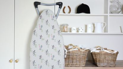 A laundry room with a washing machine, hanging laundry and a polka dot ironing board