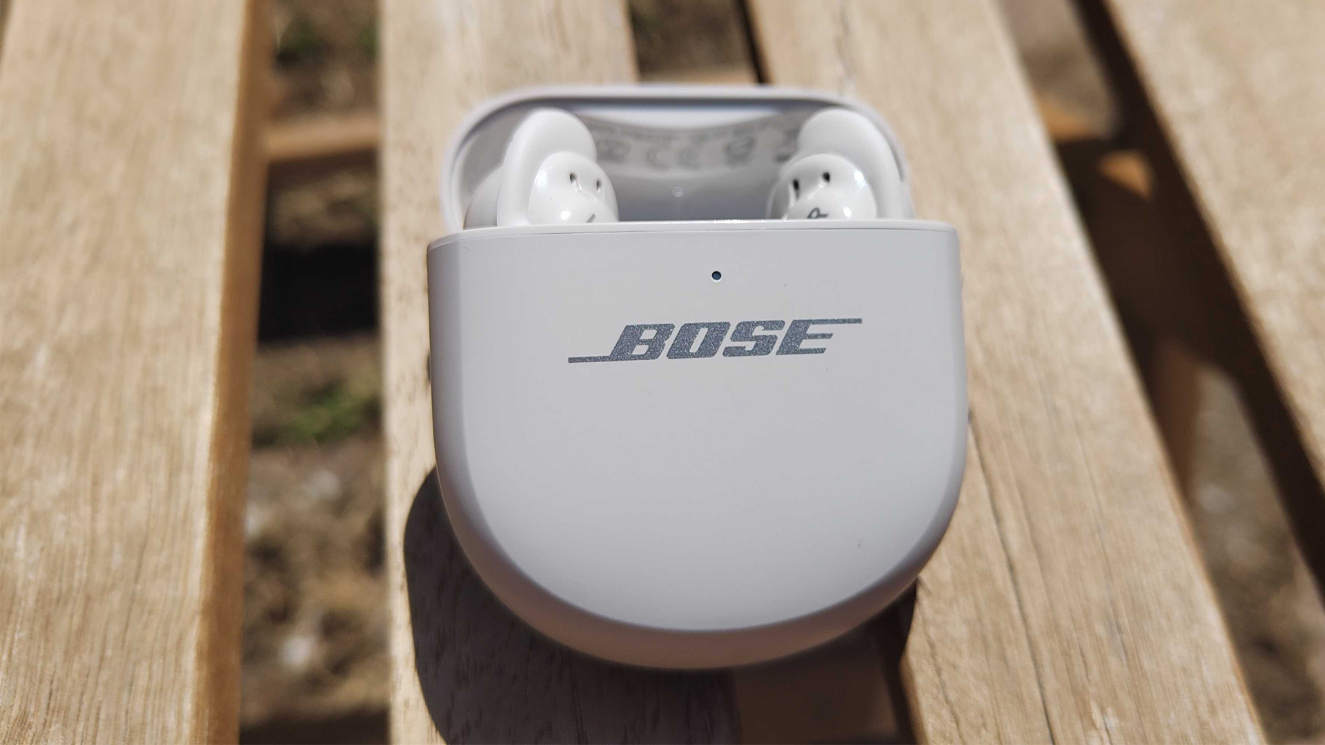 Bose QuietComfort Ultra Earbuds (2nd Gen) wireless earbuds in case on wooden garden chair