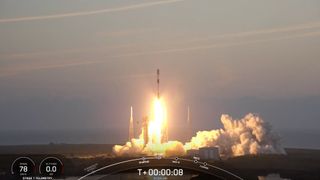 a black and white rocket launches into an early morning sky