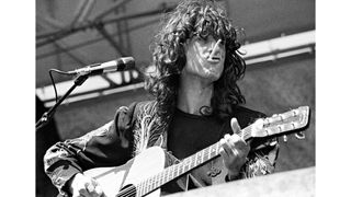 Photo of Jimmy PAGE and LED ZEPPELIN, Jimmy Page performing on stage, playing acoustic guitar, smoking a cigarette
