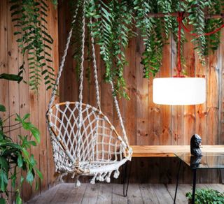garden room with timber cladding and hanging rattan chair with low pendant light