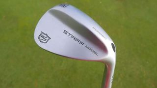 Wilson Staff Model wedge held aloft on the course to show its minimalist design