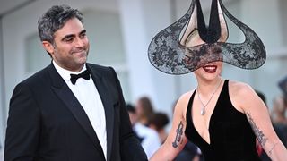 Michael Polansky smiles at Lady Gaga, who is wearing an arched lacy headpiece