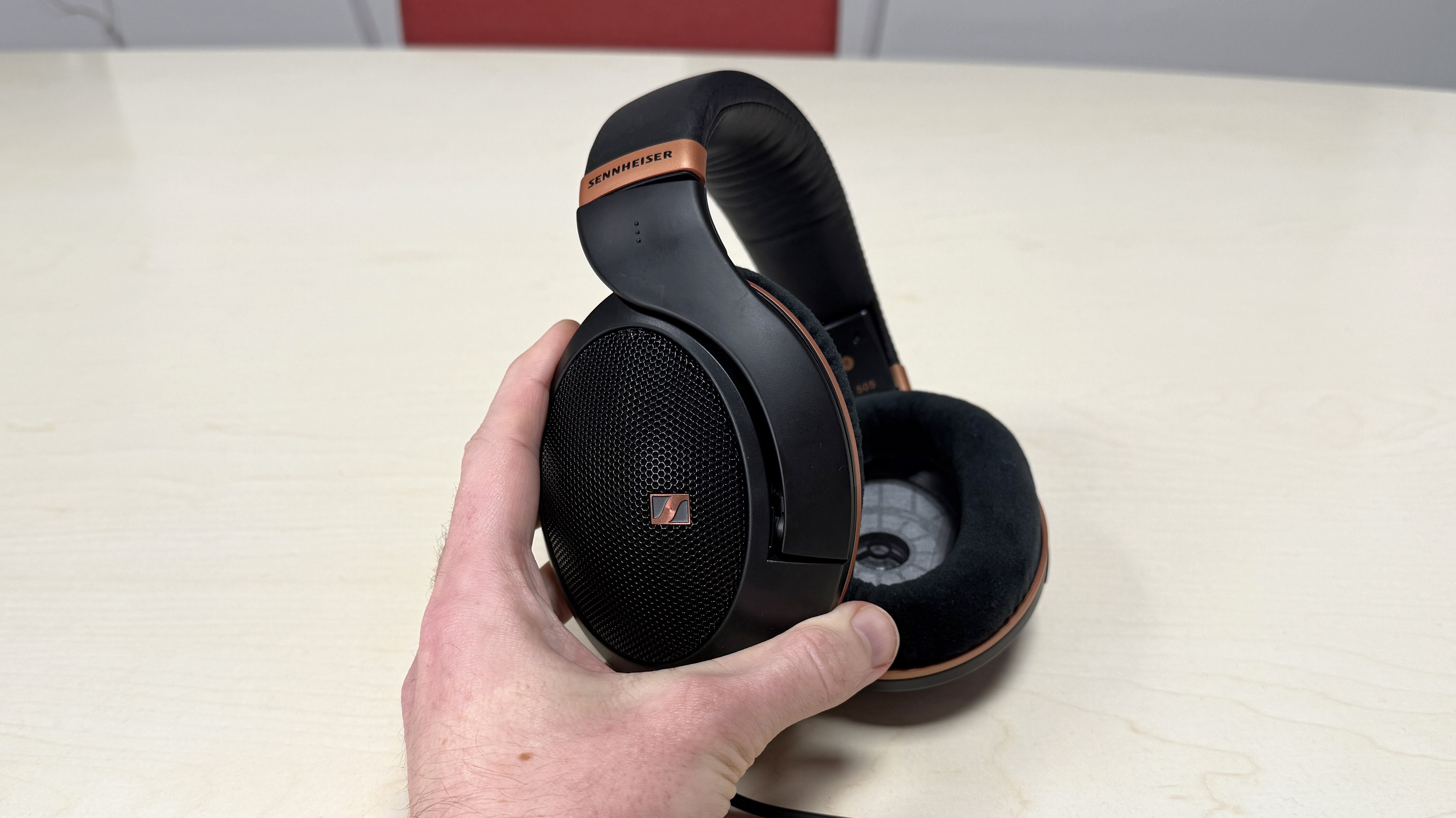 Sennheiser HD 505 headphones held in a man's hand, showing the earcup mesh