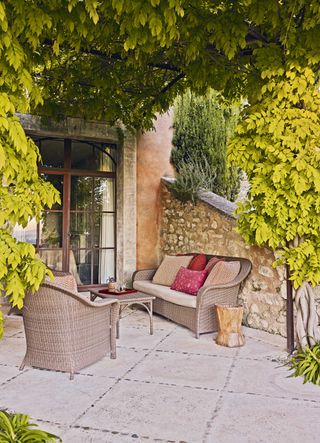traditional chairs on paving with wisteria overhead