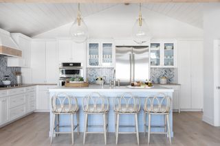 white and blue kitchen coastal style, with metallic tile backsplash, blue painted island, clear glass pendants, shiplap ceiling